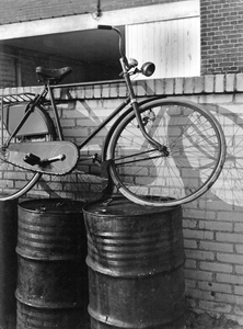 361232 Afbeelding van een fiets op een stel oliedrums.